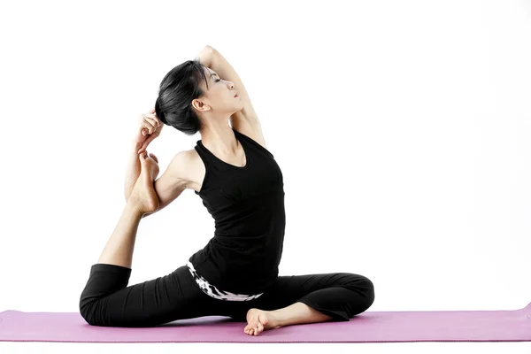 Portrait of a cute young asian female practicing yoga on a mat — Stock Photo, Image