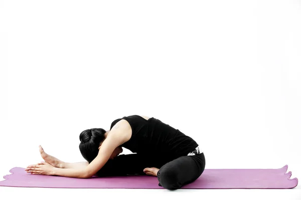 Portrait of a cute young asian female practicing yoga on a mat Royalty Free Stock Images