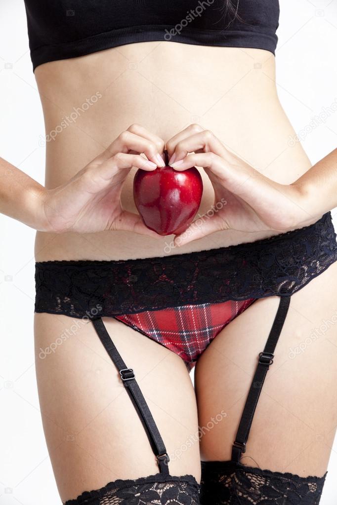 Shot of a sexy woman in black hand holding red apple