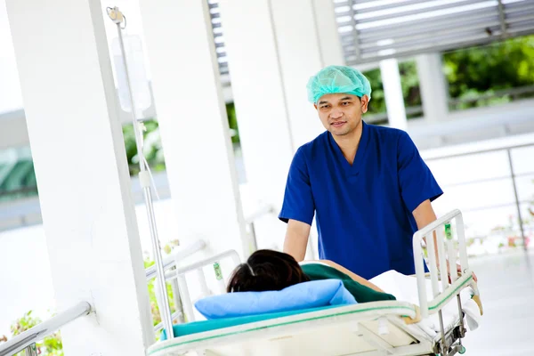 Медицинский работник перевозит пациента на тележке в операционную — стоковое фото