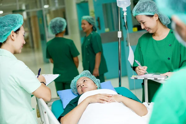 Trabajador médico moviendo al paciente en el carro del hospital al quirófano — Foto de Stock