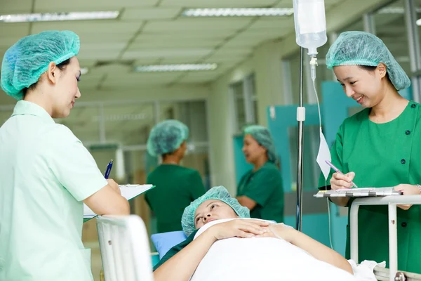 Un travailleur médical déplace un patient sur un chariot d'hôpital dans une salle d'opération — Photo