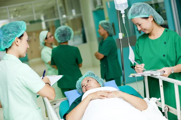 Medical worker moving patient on hospital trolley to operating room — Stock Photo, Image