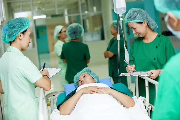 Медичний працівник переміщує пацієнта на лікарняному візку до операційної кімнати — стокове фото