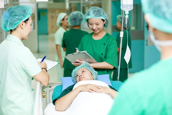 Medical worker moving patient on hospital trolley to operating room — Stock Photo, Image