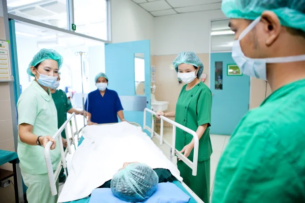 Trabalhadores que mudam o paciente para o centro cirúrgico — Fotografia de Stock