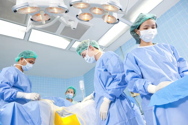 Several surgeons surrounding patient on operation table during their work — Stock Photo, Image