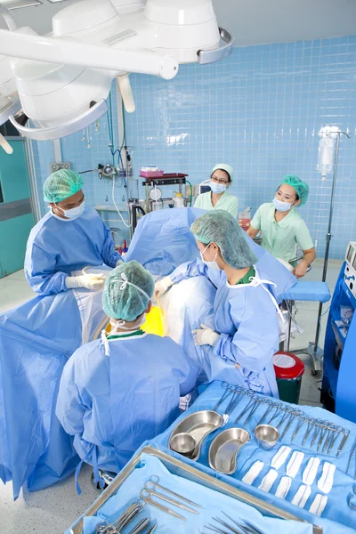 Varios cirujanos que rodean al paciente en la mesa de operaciones durante su trabajo — Foto de Stock