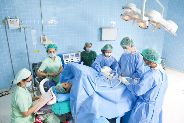 Mehrere Chirurgen umgeben Patienten während ihrer Arbeit auf dem Operationstisch — Stockfoto