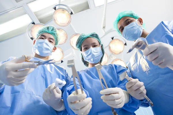 Abaixo a visão de cirurgiões segurando instrumentos médicos nas mãos e olhando para o paciente — Fotografia de Stock