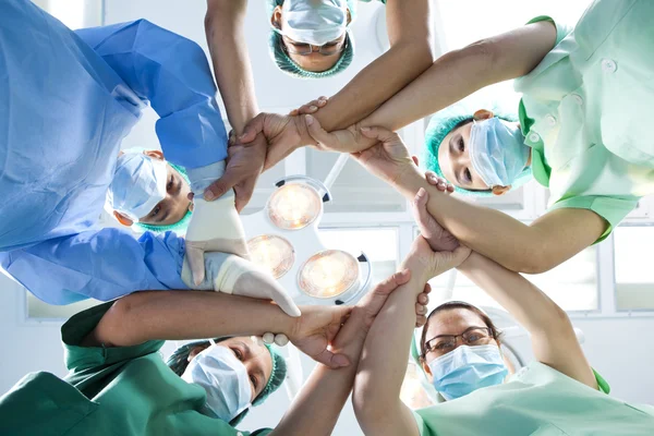 Pequeno grupo de equipe médica unindo as mãos, vista de ângulo de olhos da formiga . — Fotografia de Stock
