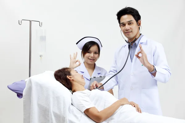 Retrato de um médico com seus colegas conversando com um paciente em segundo plano — Fotografia de Stock