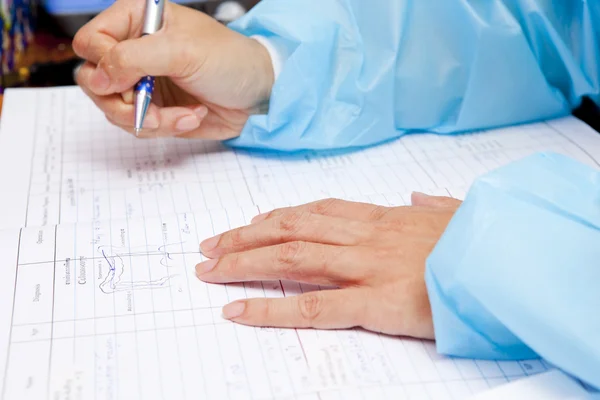 Female doctor writing on medical chart — Stock Photo, Image
