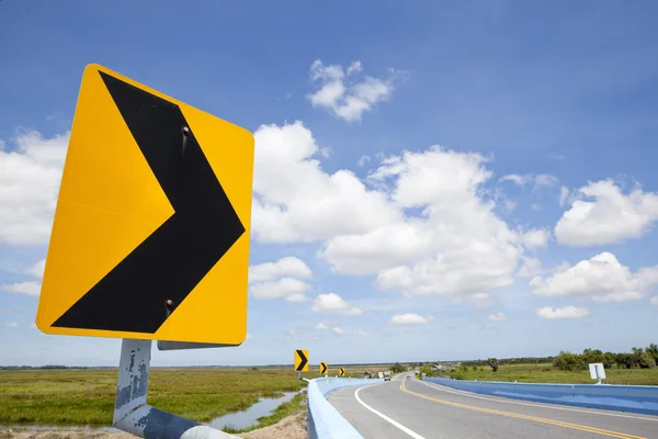 Gevaar kromme verkeersbord met blauwe hemel — Stockfoto