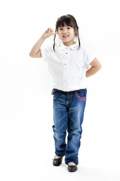 Портрет маленькой девочки в белой рубашке и синих джинсах, веселящихся на белом фоне — стоковое фото