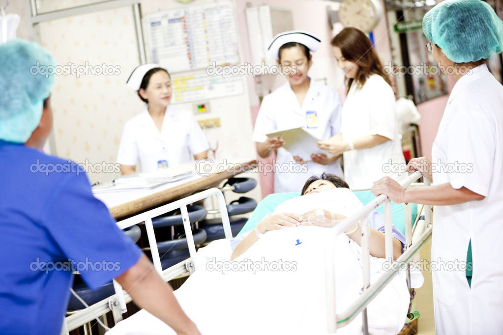 Worker moving patient on hospital trolley to operating room