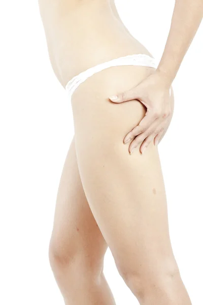 Une jeune fille en sous-vêtements blancs vérifiant la cellulite sur son cul, isolée sur un fond blanc — Photo