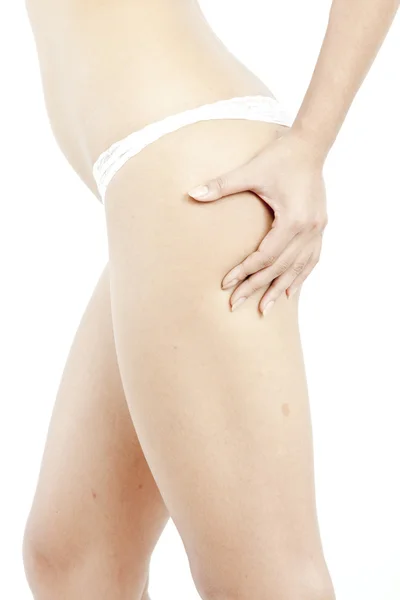 Ein junges Mädchen in weißer Unterwäsche überprüft Cellulite auf ihrem Hintern, isoliert auf weißem Hintergrund — Stockfoto