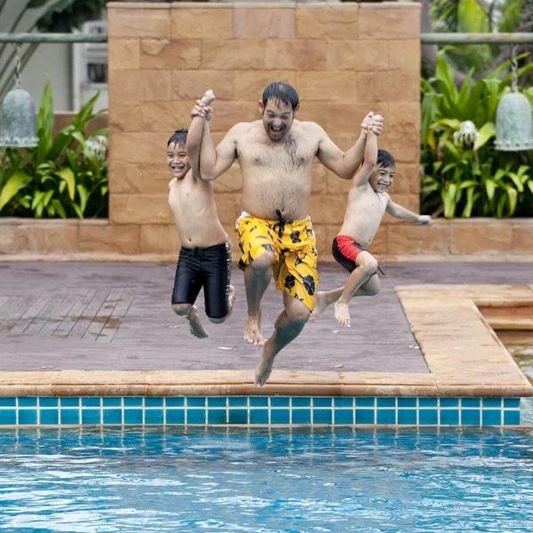 Счастливый отец прыгает в бассейн со своими сыновьями — стоковое фото