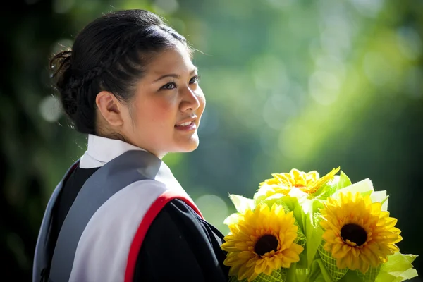 黄色い花を持つ若い卒業女性 — ストック写真