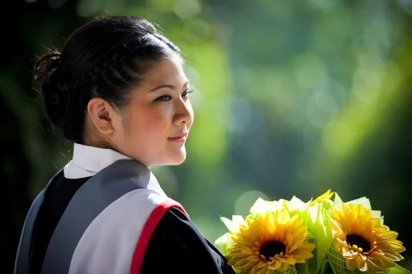 Young graduation woman with yellow flowers — Stock Photo, Image