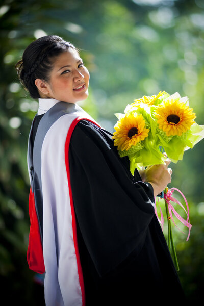 Young graduation woman with yellow flowers