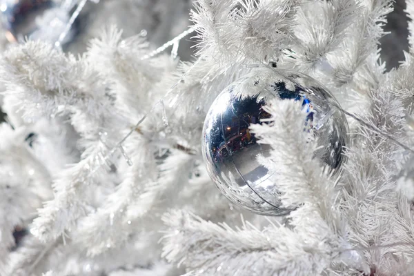 Un'immagine ravvicinata di una sfera ornamentale decorativa bianca di Natale su un ramo di abete bianco con l'illuminazione blu . — Foto Stock