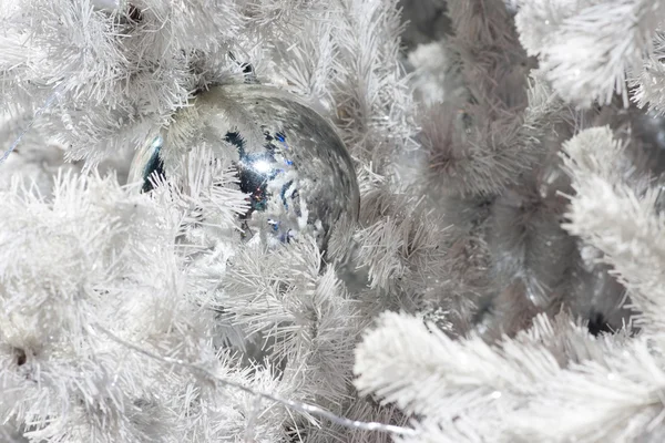 A close up image of a white decorative Christmas ornamental orb on a white fir tree branch with the blue lighting. — Stock Photo, Image