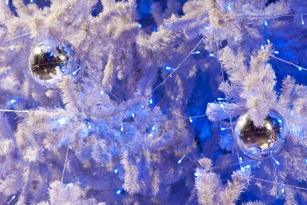 Zblízka obraz bílá dekorativní vánoční ozdobné koule na větev stromu bílé jedle s modrým osvětlením. — Stock fotografie