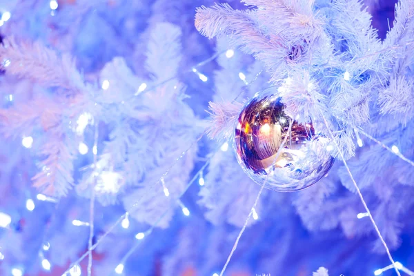 Une image rapprochée d'une orbe décorative de Noël blanche sur une branche de sapin blanc avec l'éclairage bleu . — Photo