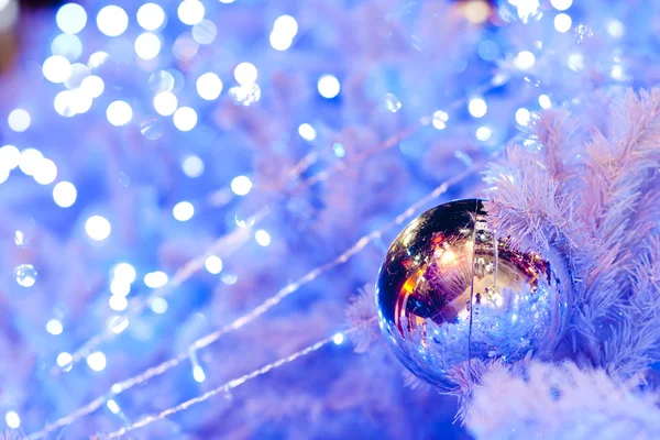关闭了一个白色装饰圣诞观赏的圆球上白杉树分支的蓝色照明与形象. — 图库照片