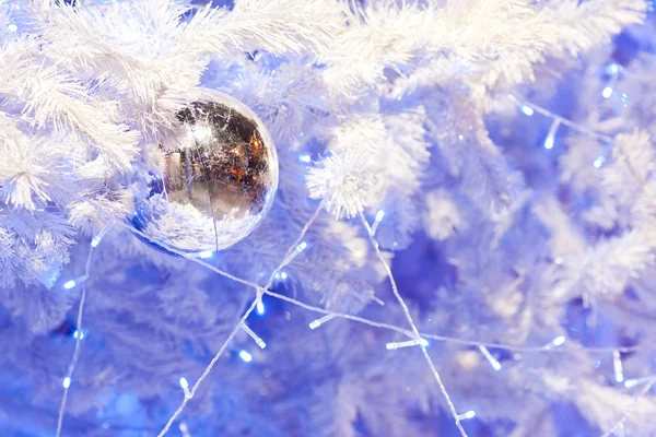 Une image rapprochée d'une orbe décorative de Noël blanche sur une branche de sapin blanc avec l'éclairage bleu . — Photo