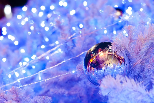 Un'immagine ravvicinata di una sfera ornamentale decorativa bianca di Natale su un ramo di abete bianco con l'illuminazione blu . — Foto Stock