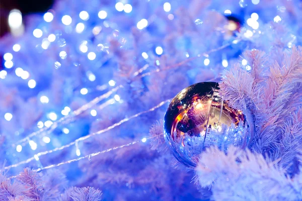 Una imagen de cerca de un orbe ornamental de Navidad decorativo blanco en una rama de abeto blanco con la iluminación azul . —  Fotos de Stock