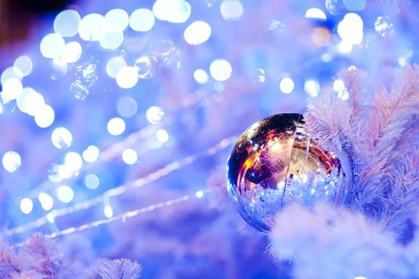 Un'immagine ravvicinata di una sfera ornamentale decorativa bianca di Natale su un ramo di abete bianco con l'illuminazione blu . — Foto Stock