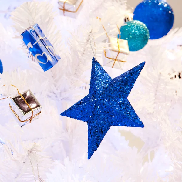 A close up image of a white decorative Christmas ornamental orb on a white fir tree branch with the blue lighting. — Stock Photo, Image