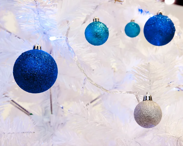 A close up image of a white decorative Christmas ornamental orb on a white fir tree branch with the blue lighting. — Stock Photo, Image