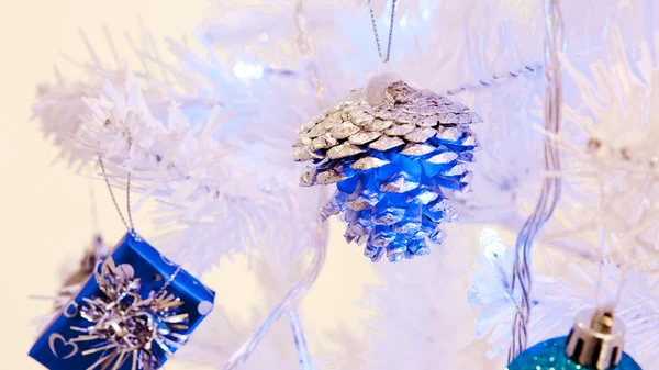 A close up image of a white decorative Christmas ornamental orb on a white fir tree branch with the blue lighting. — Stock Photo, Image