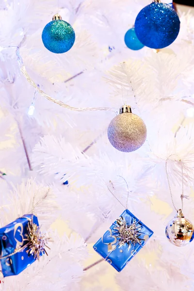 A close up image of a white decorative Christmas ornamental orb on a white fir tree branch with the blue lighting. — Stock Photo, Image