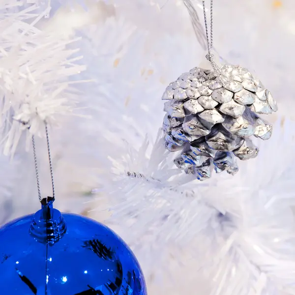 नीले प्रकाश के साथ एक सफेद फायर ट्री शाखा पर एक सफेद सजावटी क्रिसमस सजावटी ऑर्ब की एक नज़दीक छवि . — स्टॉक फ़ोटो, इमेज