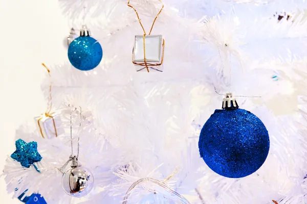 Un'immagine ravvicinata di una sfera ornamentale decorativa bianca di Natale su un ramo di abete bianco con l'illuminazione blu . — Foto Stock