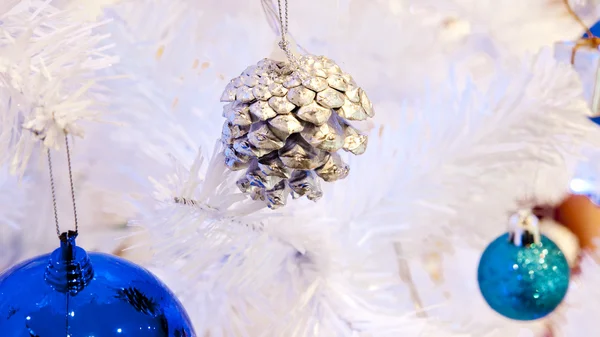 Крупный план белого декоративного рождественского шара на ветке белой елки с синим освещением . — стоковое фото
