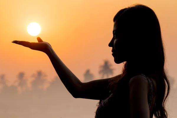 Portrait of young woman as silhouette and hand holding the sun — Stock Photo, Image