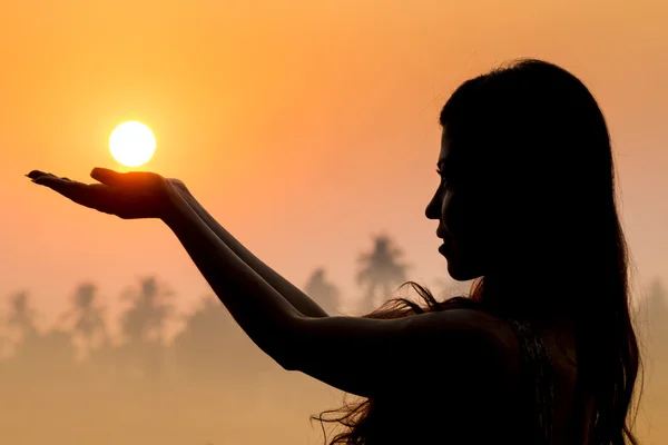 Portrait of young woman as silhouette and hand holding the sun — Stock Photo, Image