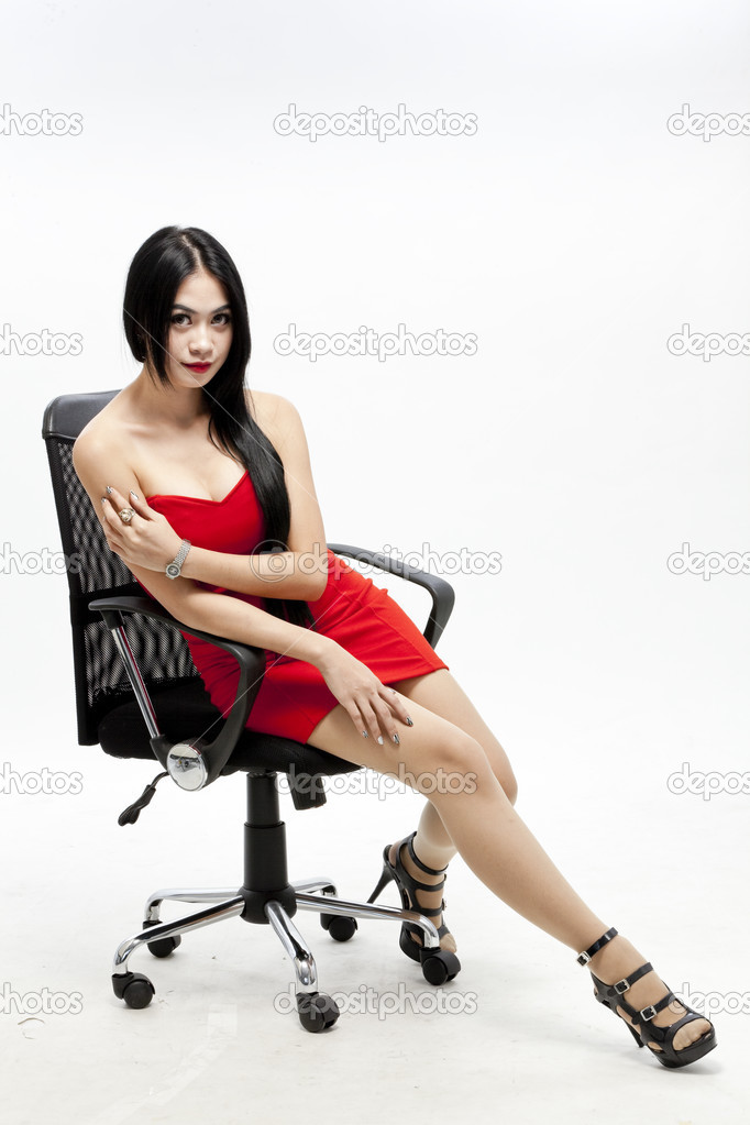 Young gorgeous asian in red dress on the chair, isolated on white, studio shot