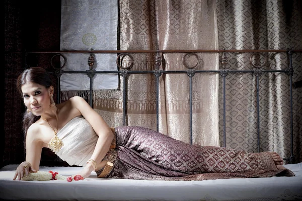 Gorgeous asian woman in thai dress lying on bed — Stock Photo, Image