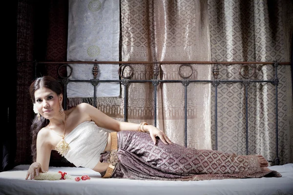 Πανέμορφο ασιατική γυναίκα σε Ταϊλάνδης φόρεμα ξαπλωμένη στο κρεβάτι — Φωτογραφία Αρχείου