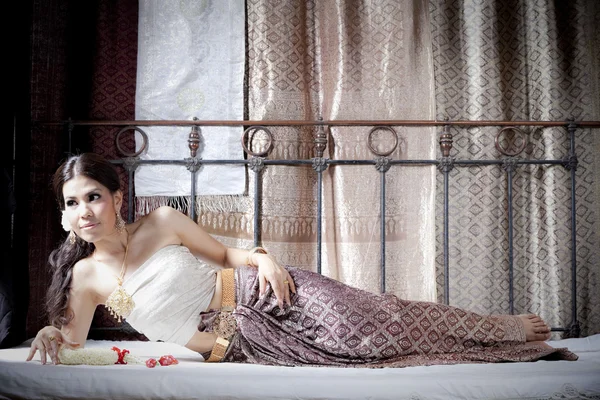 Wspaniały azjatyckie kobiety w sukienka tajski, leżąc na łóżku — Zdjęcie stockowe
