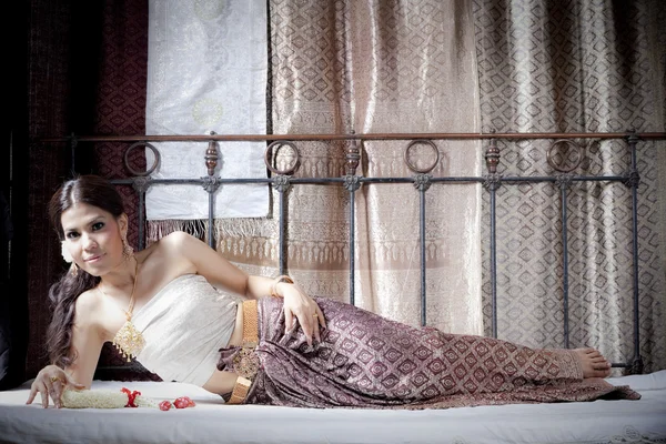 Nádherná asijská žena v thajské oblečení ležící na posteli — Stock fotografie