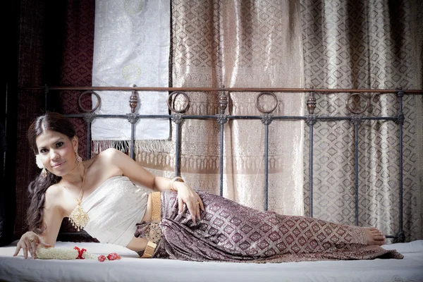 Nádherná asijská žena v thajské oblečení ležící na posteli — Stock fotografie